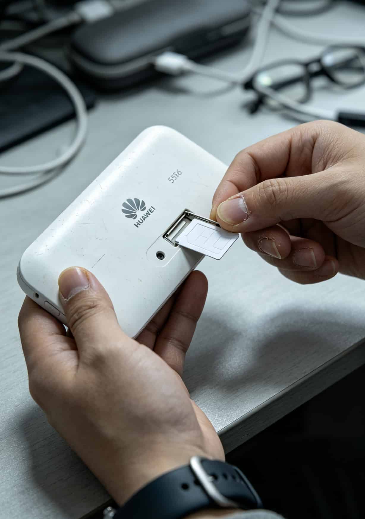 绿灯闪一夜没网?9块钱105g流量卡和华为随身WiFi到底配不配 华为E5576机身侧面SIM卡槽和复位孔位置,手指正在插卡